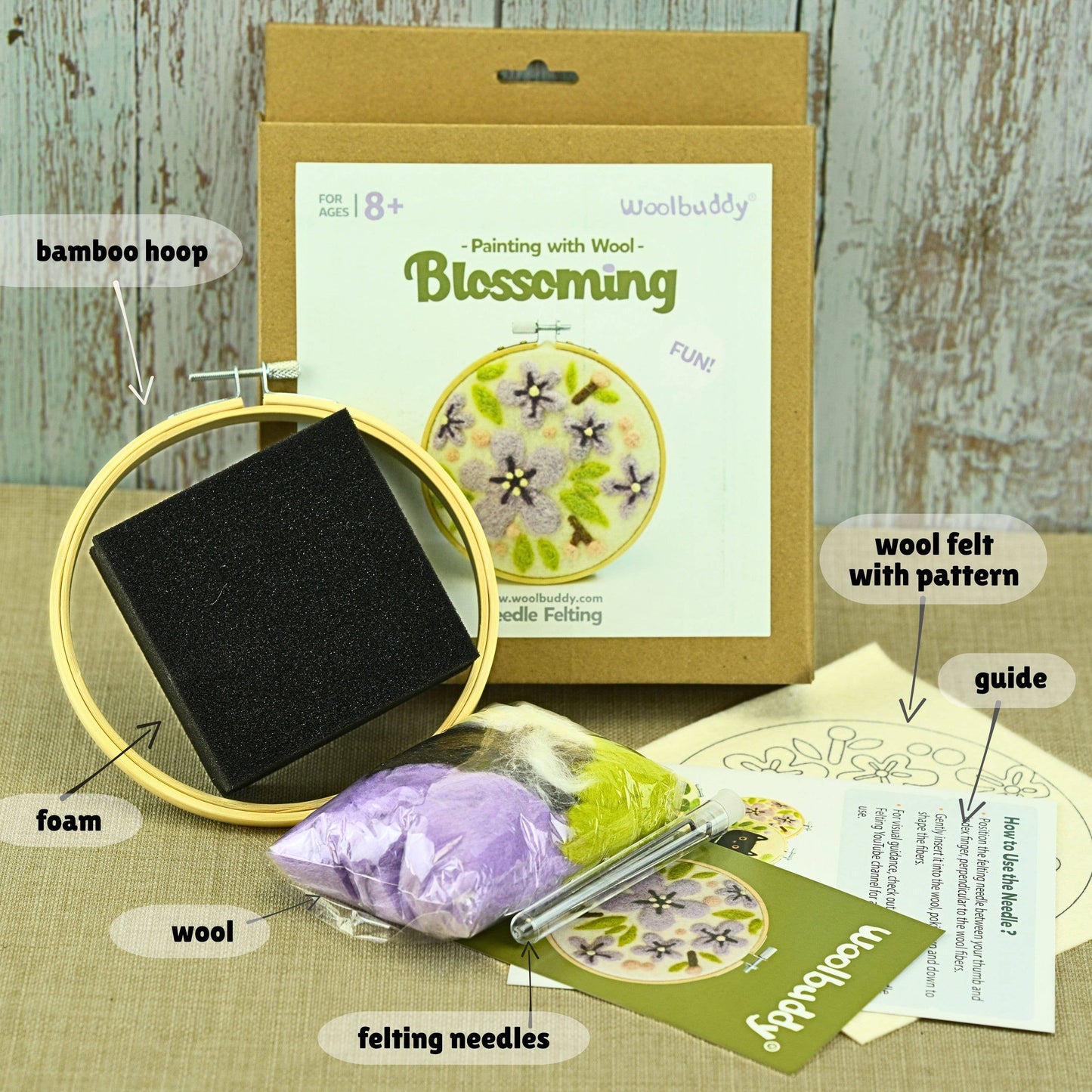 Felting kit with bamboo hoop, wool felt, and felting needles on a wooden surface.