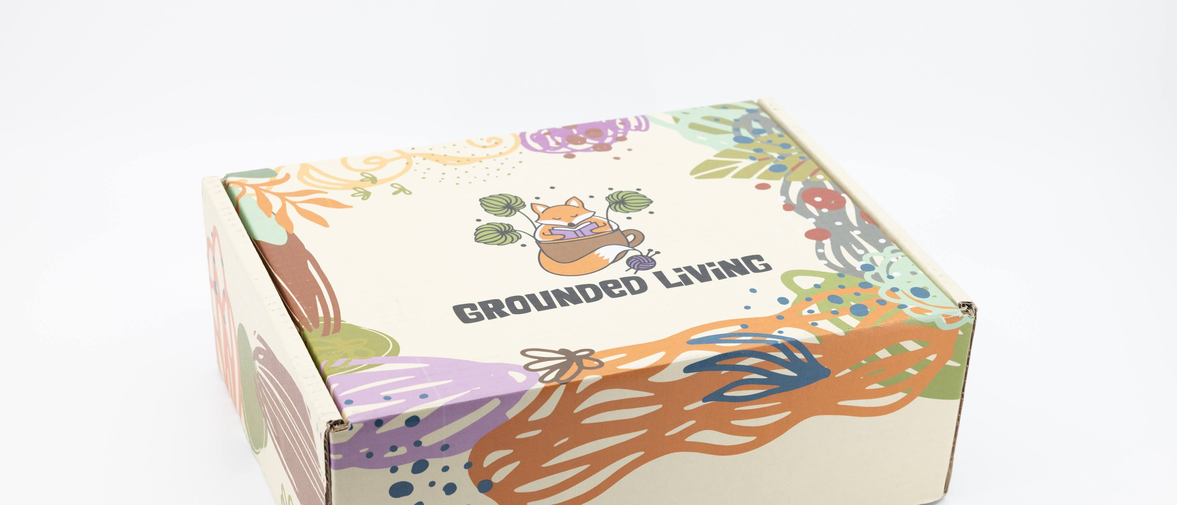 Colorful box with 'Grounded Living' branding and nature-themed illustrations on a white background