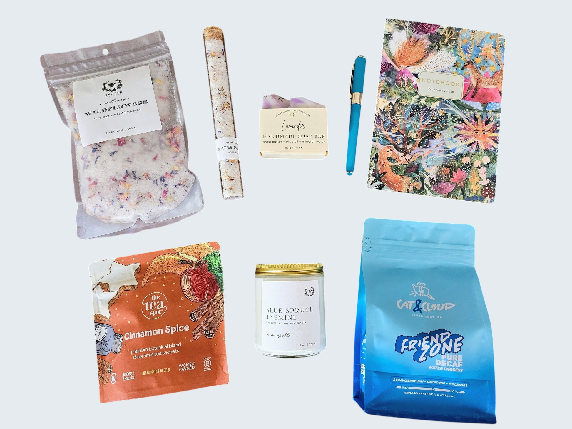 A top down overlay shot of all the luxurious and premium quality products for her: Wildflower bath soak tube and refill bag, vibrant fantasy journal with emerald green pen, delicious cinnamon spice tea, fragrant blue  spruce jasmine candle, and delicious small batch decaf coffee beans from Cat & Cloud located in Santa Cruz, CA.